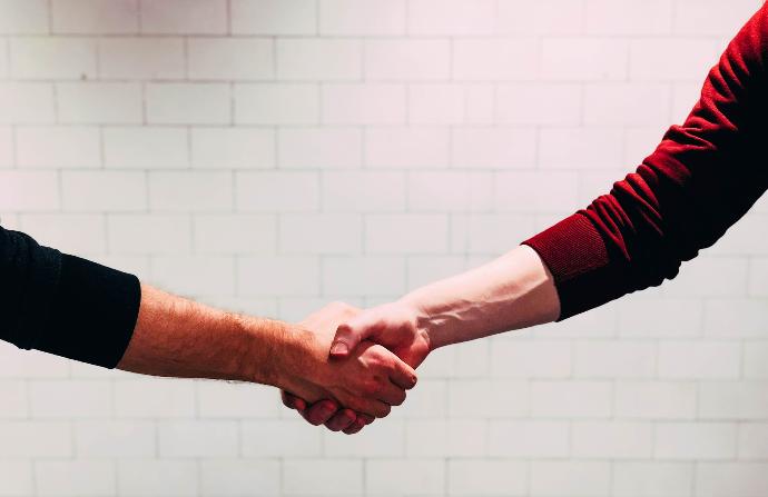 valeurs two person shaking hands near white painted wall