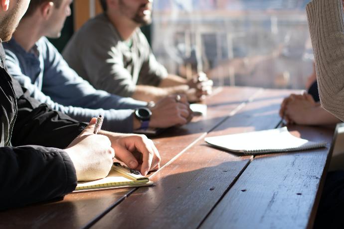 entreprise people sitting on chair in front of table while holding pens during daytime
